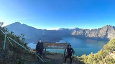 Due persone stanno in piedi sul bordo del cratere del Monte Rinjani